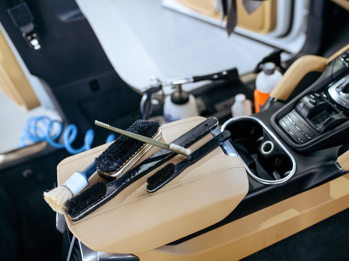 Reinigungsbürsten auf der Mittelarmlehne eines Autos mit hellem Leder