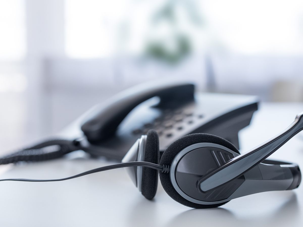 Telefon und Headset auf einem hellen Schreibtisch